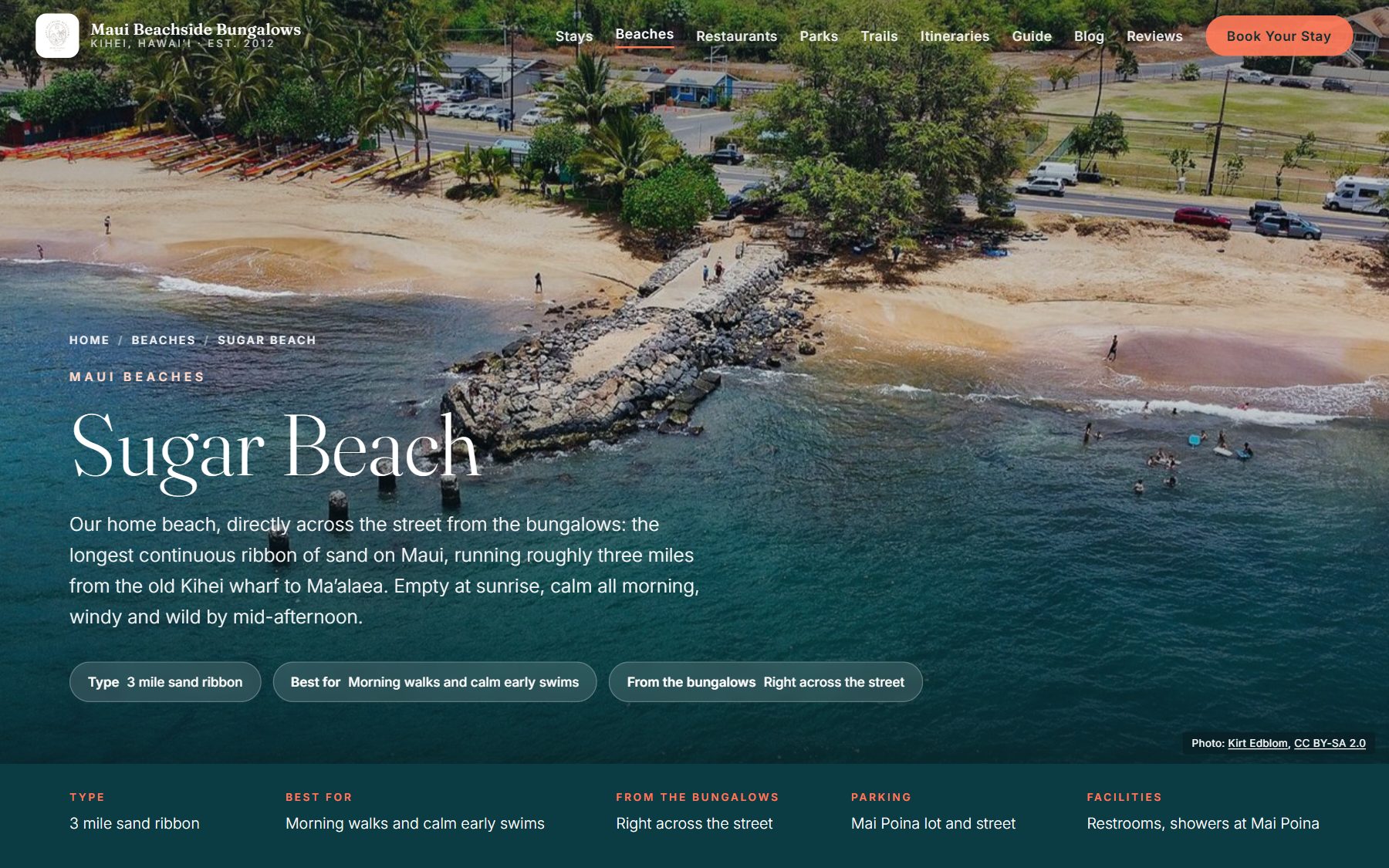 Guide page titled Sugar Beach over an aerial photo of a rock jetty, sandy shore and coast road, with an introduction, three fact chips, a row of details on type, parking and facilities, and a photo credit at lower right.