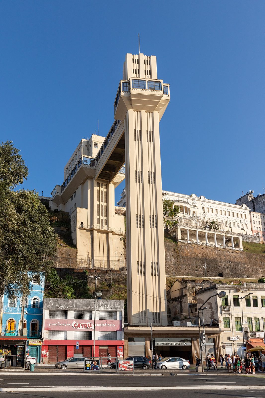 The cream art deco tower of the Lacerda Elevator rising from the lower town of Salvador, joined by a high bridge to its upper station on the escarpment