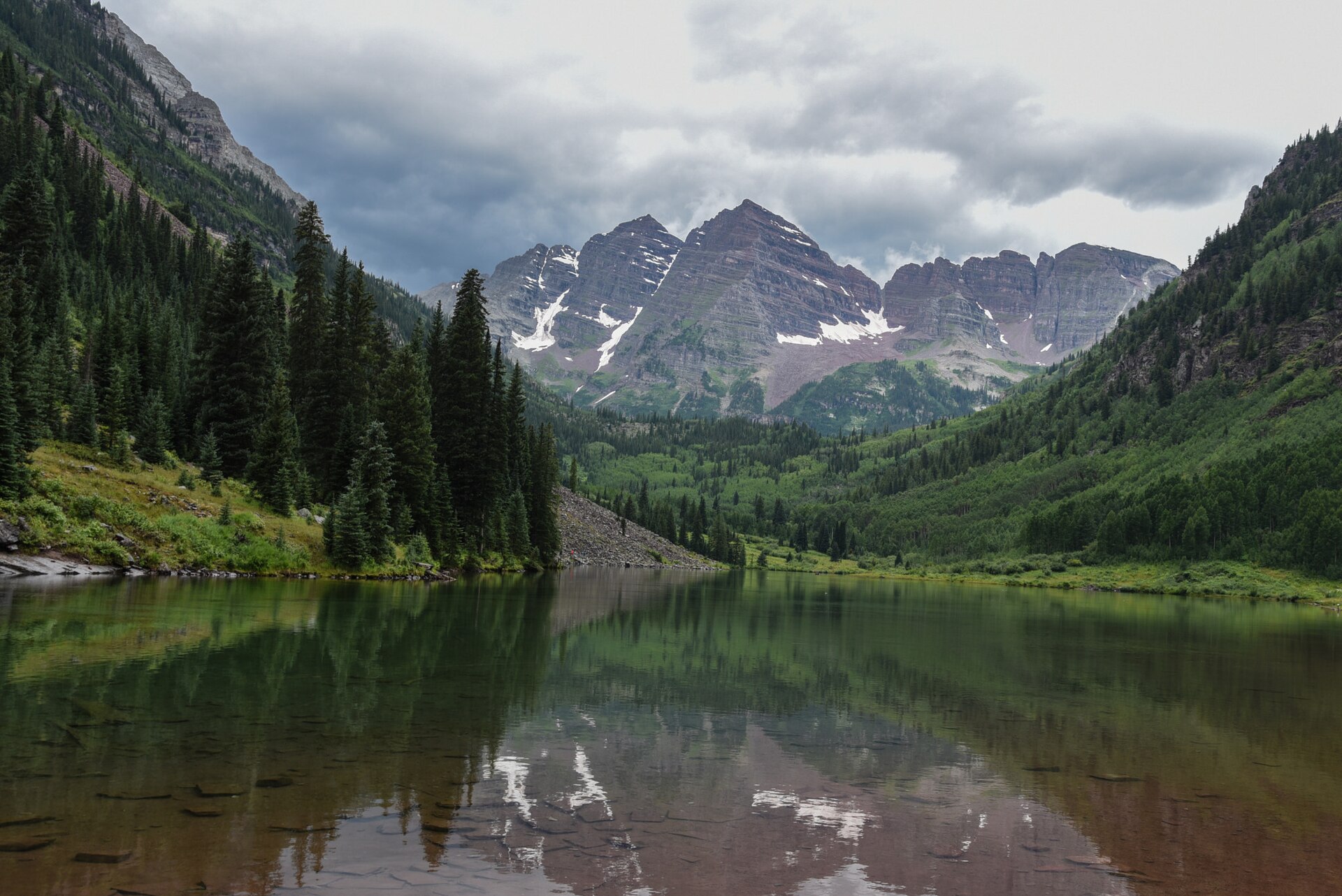 The Maroon Bells and their reflection in Maroon Lake under early-autumn snow near Aspen