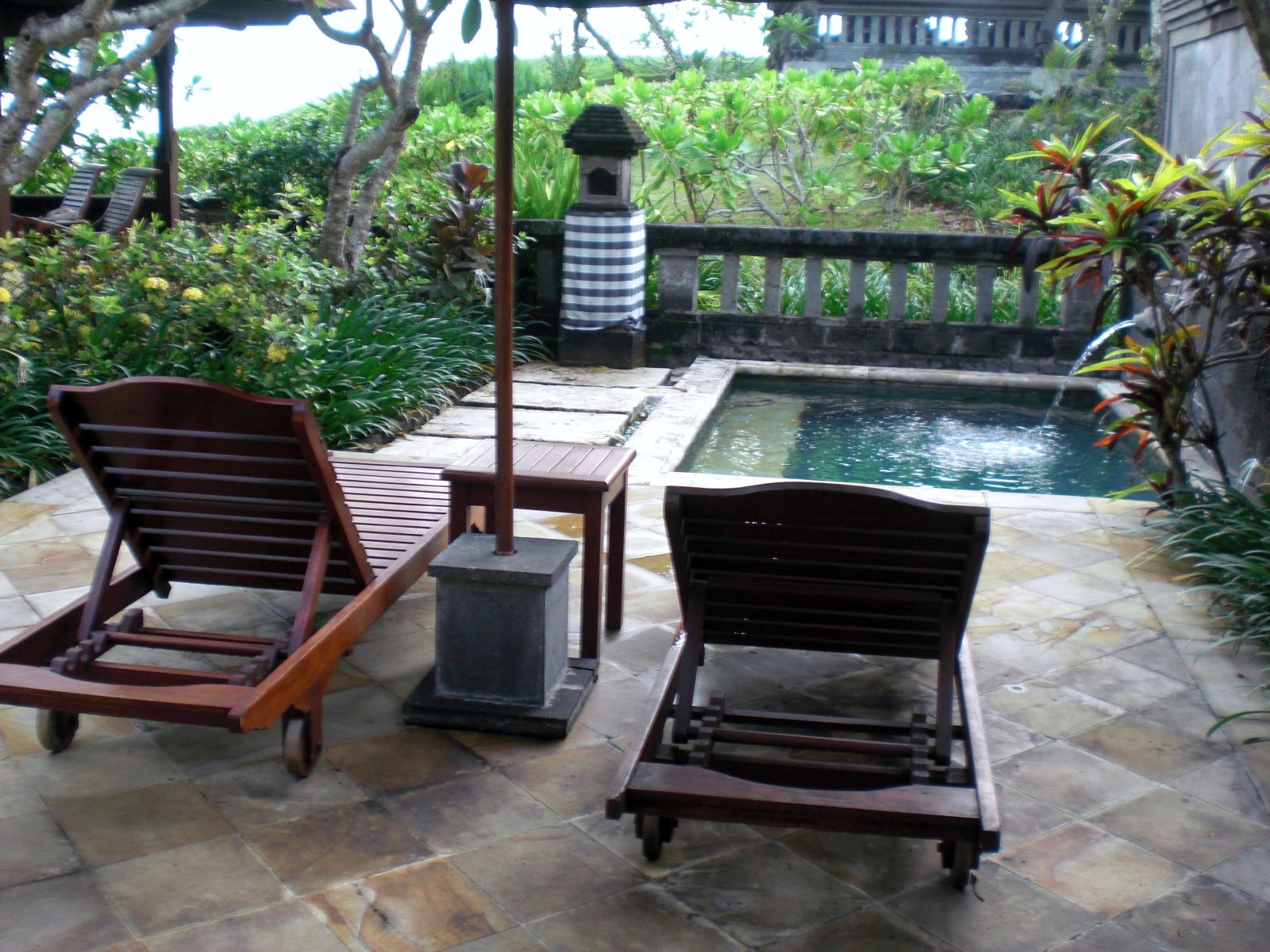 A private Balinese villa with a swimming pool bordered by tropical greenery and an open-sided pavilion.