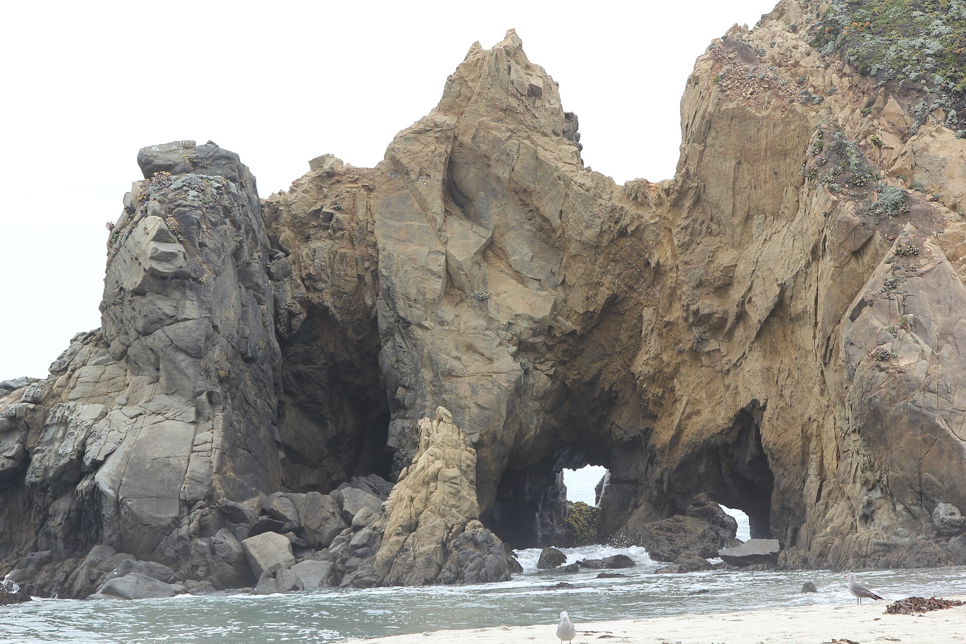 The purple-tinted sand and offshore rock arch at Pfeiffer Beach in Big Sur