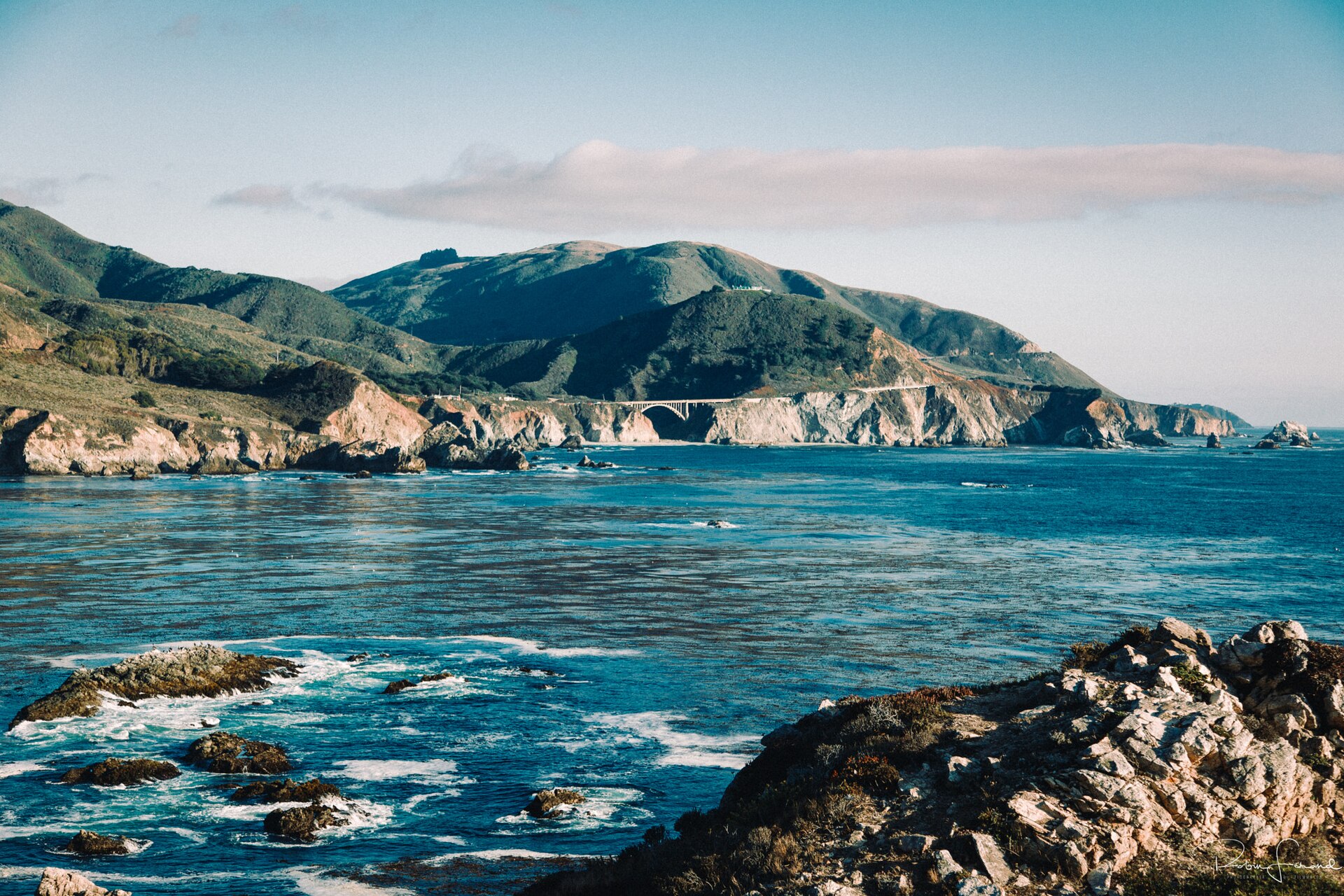 Bixby Creek Bridge spanning a steep canyon on the Big Sur coast, with Highway 1 curving along the cliffs above the Pacific