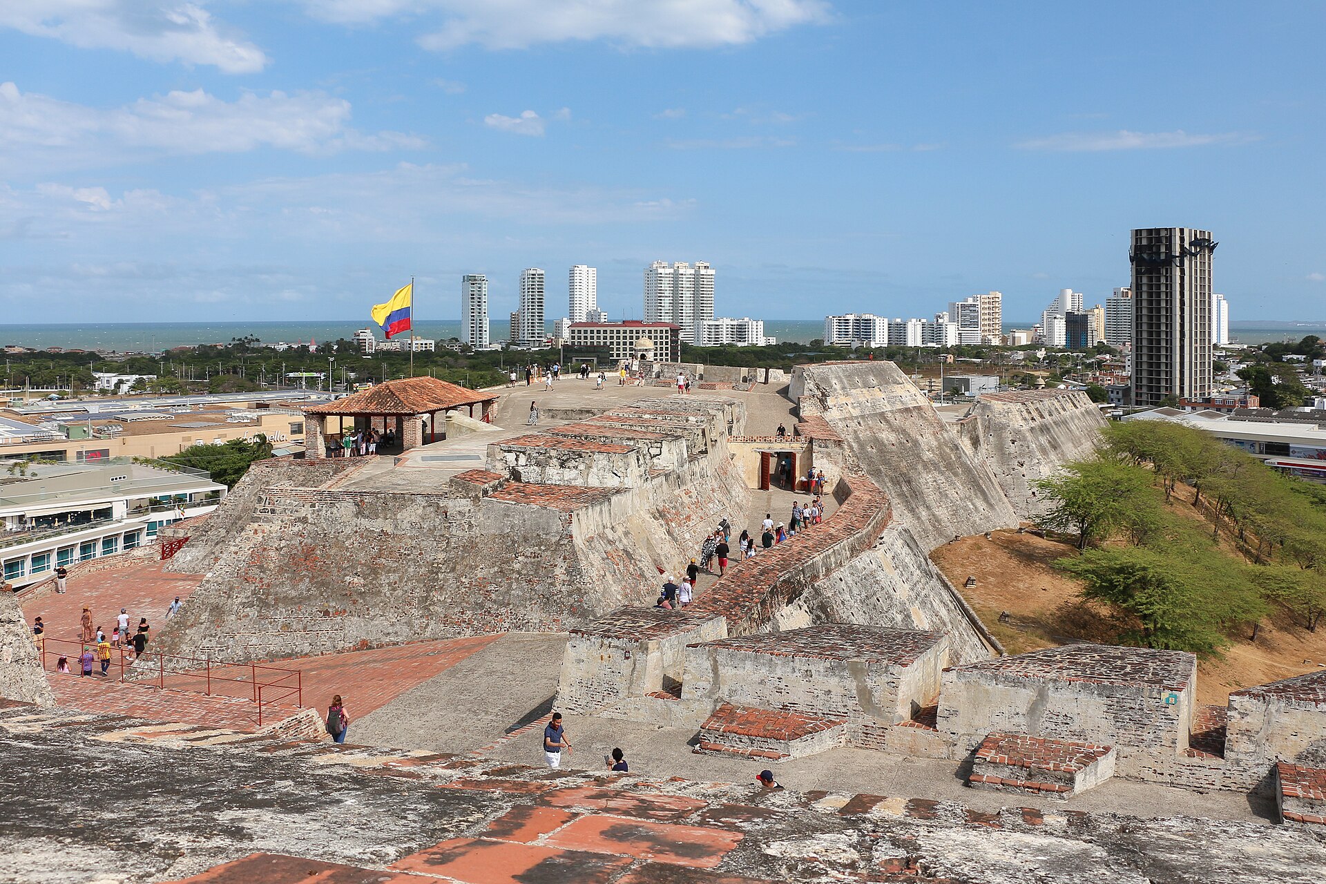 The sloping stone bastions of the Castillo San Felipe de Barajas fortress rising above Cartagena under a bright sky.