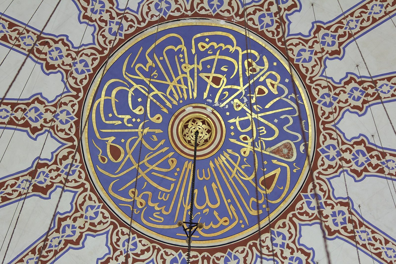An ornate, gold-patterned ceiling extends over a series of arches and columns, with decorated walls visible below.