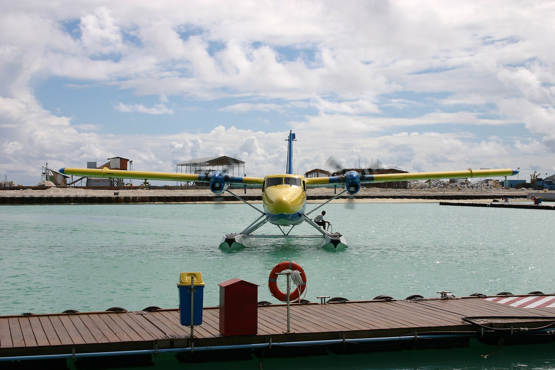 A seaplane on floats moored beside a wooden jetty on a turquoise Maldives lagoon