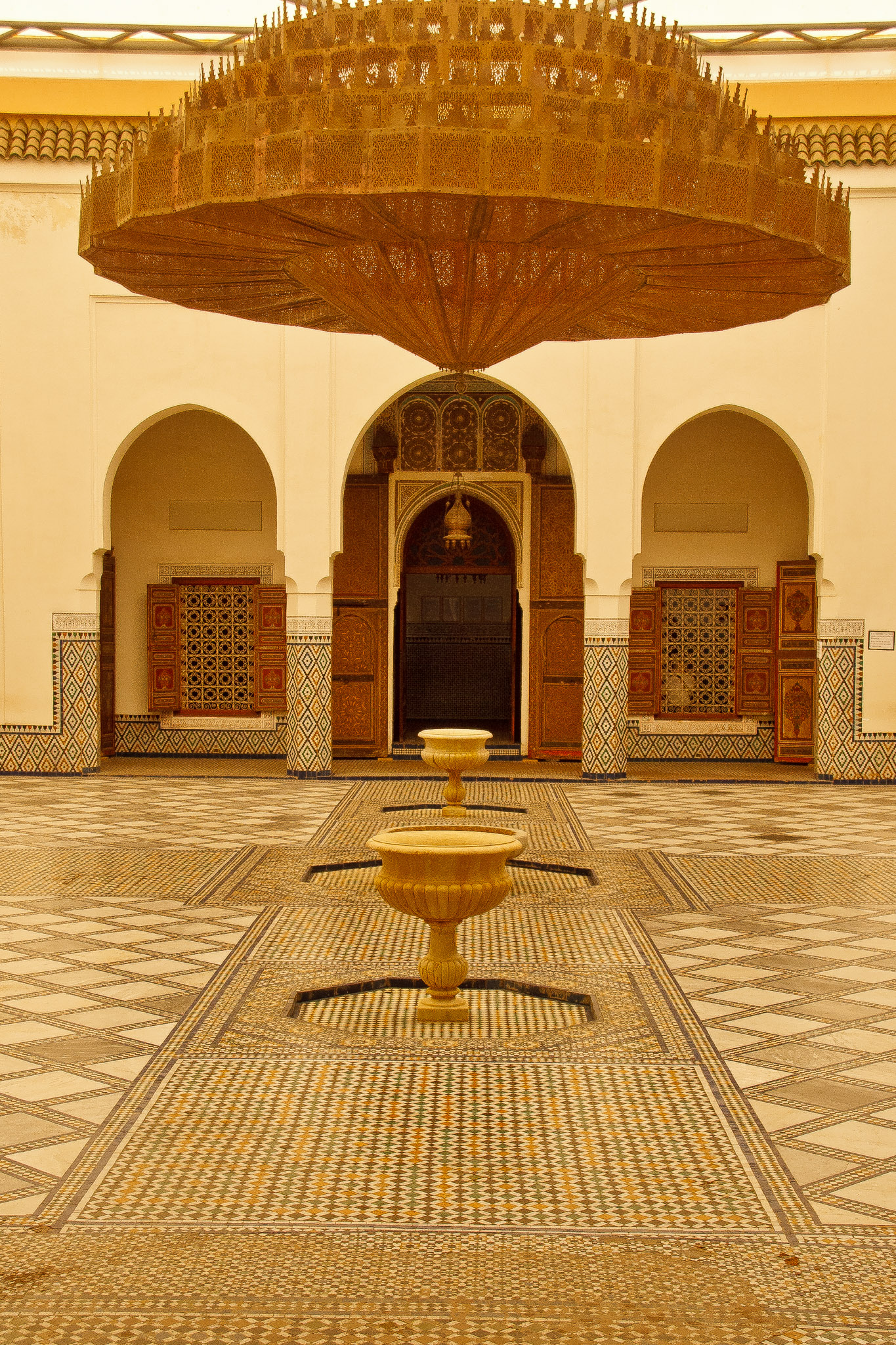 Interior courtyard of a Marrakech riad with a central fountain, tilework, and rooms opening onto the patio
