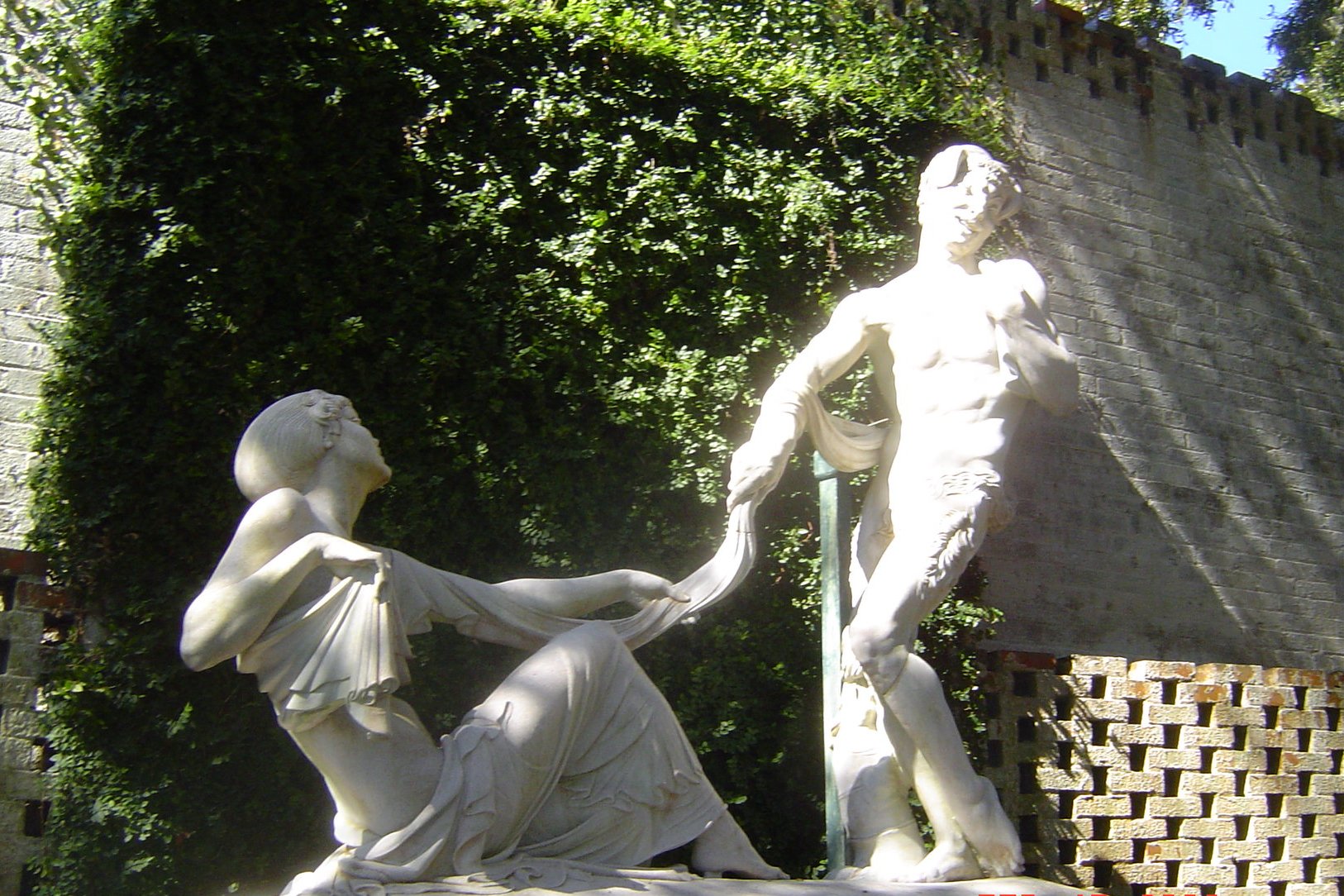 A figurative bronze sculpture in a formal garden at Brookgreen Gardens near Murrells Inlet, South Carolina, with clipped hedges and live oaks behind.