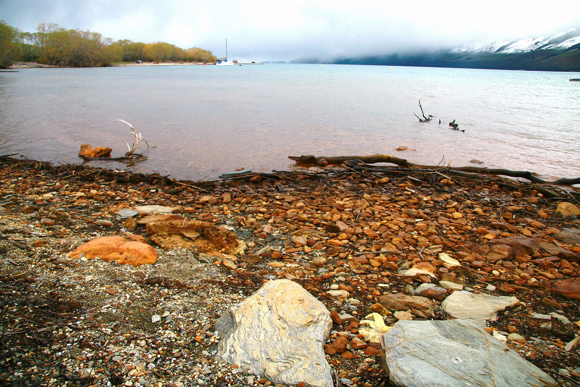 The road to Glenorchy running along the shore at the head of Lake Wakatipu beneath high mountains.