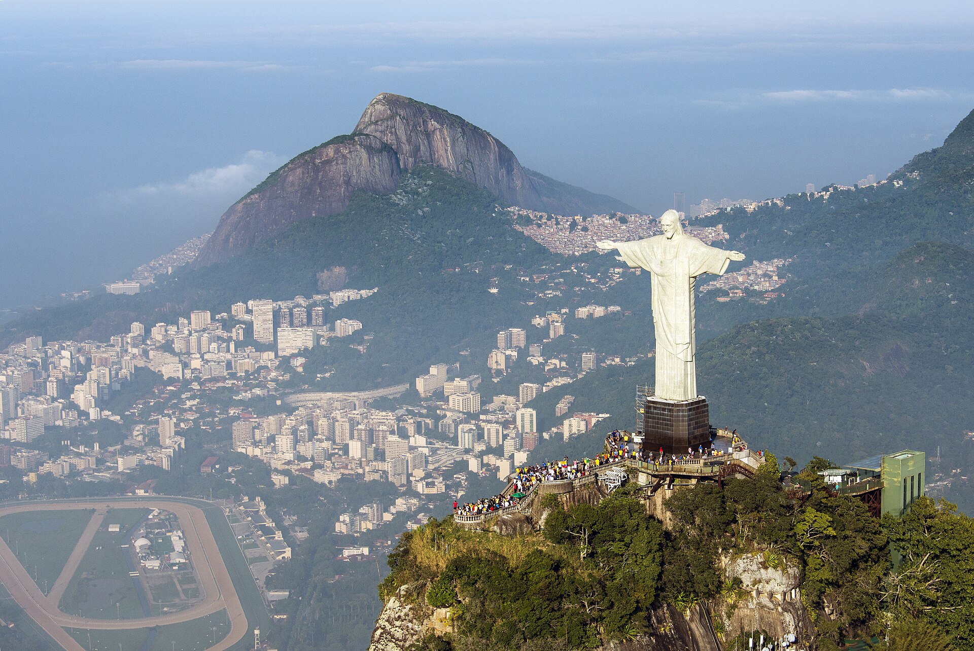 The Christ the Redeemer statue on the Corcovado peak above Rio de Janeiro, with the city and the crowded viewing platform below.