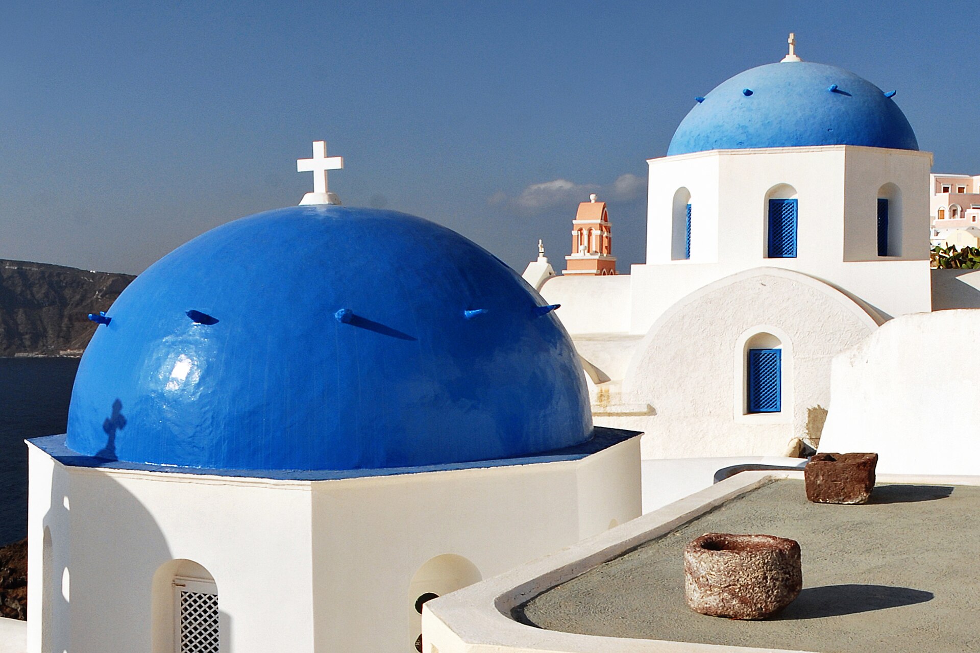 Blue-domed white church on the cliff edge at Firostefani with the caldera behind