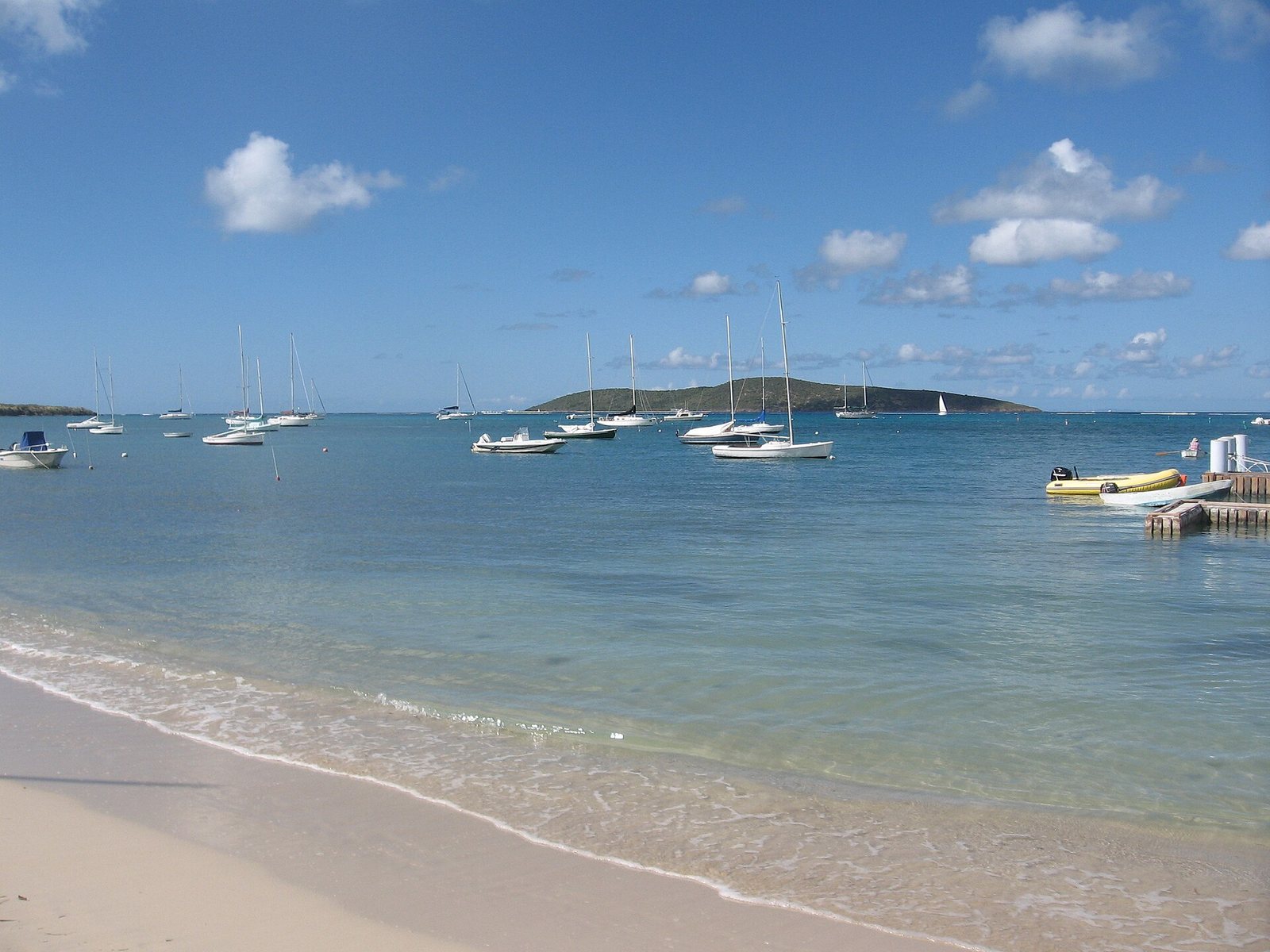 Teague Bay beach on the East End of St. Croix, with sailboats moored offshore and Buck Island on the horizon.