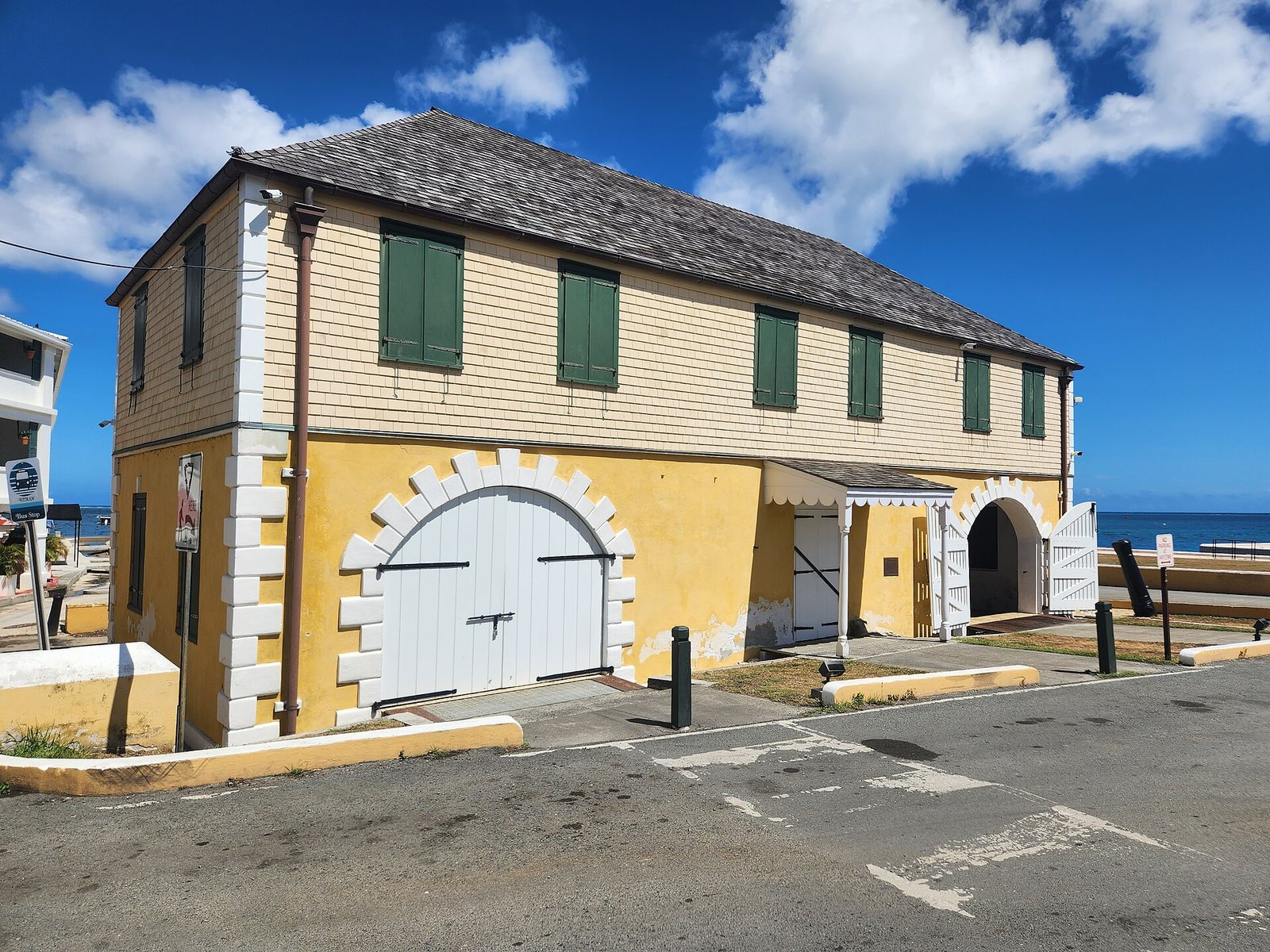 The yellow Scale House in Christiansted, a two-storey Danish-era building with green shutters and a white arched doorway.