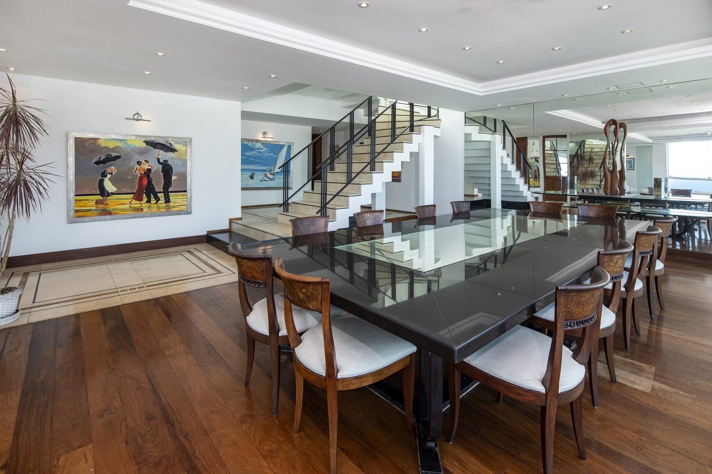 Dining room with a marble staircase and dark hardwood floors inside the Copacabana Penthouse