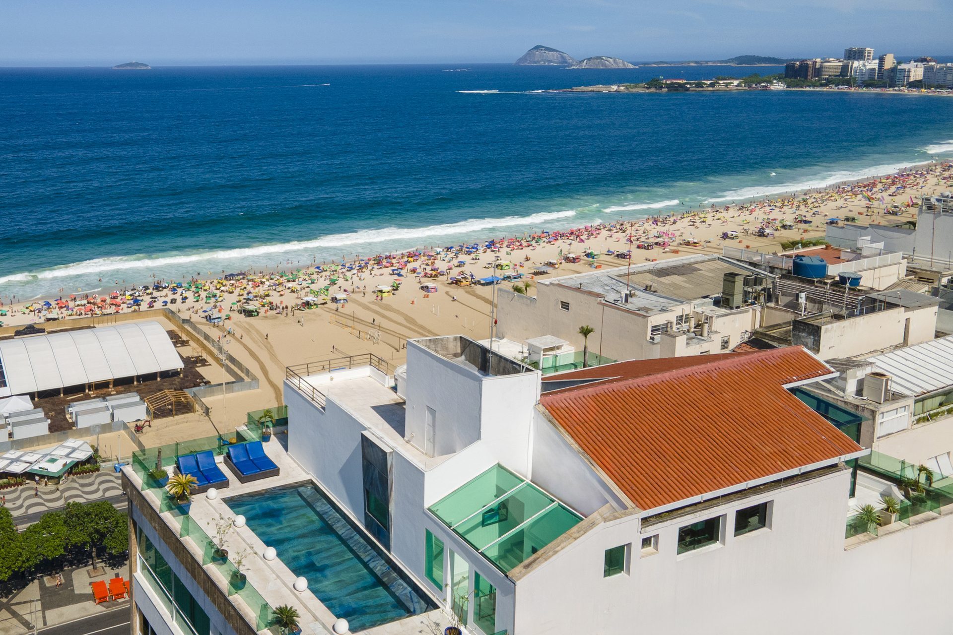 Aerial view of the Copacabana Penthouse's rooftop pool above the beach, with the Rio de Janeiro coastline beyond
