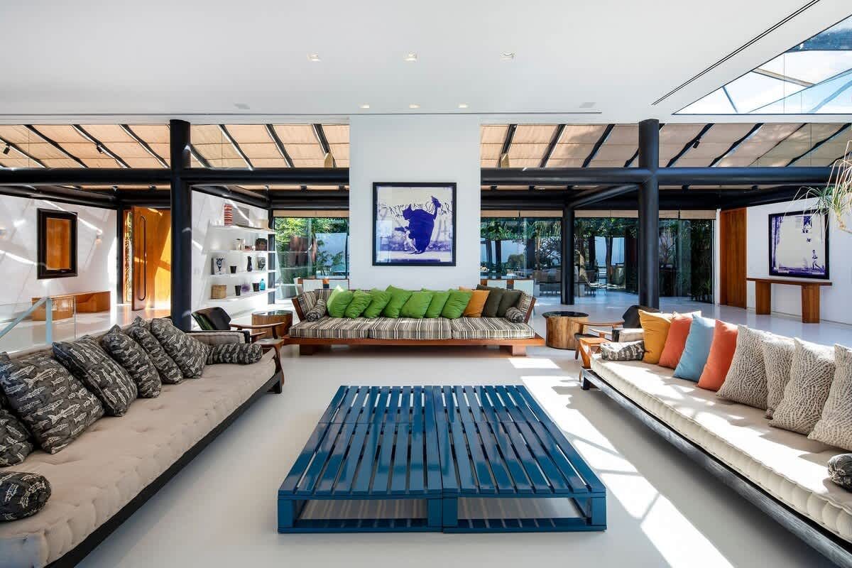 Double-height living pavilion at the São Conrado Beach View Villa, with built-in seating and framed artwork beneath a pitched glass roof
