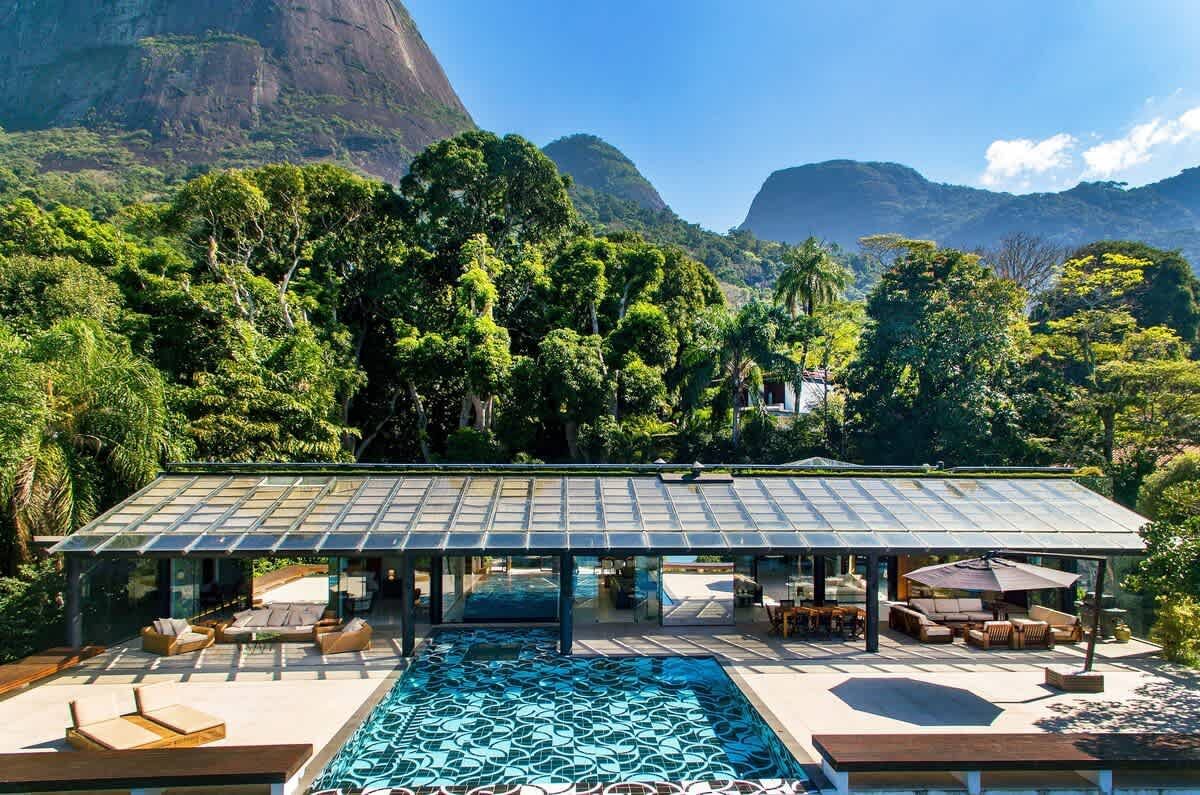 Infinity pool with a flower-draped daybed pergola at the São Conrado Beach View Villa, looking toward Pedra da Gávea and the Atlantic