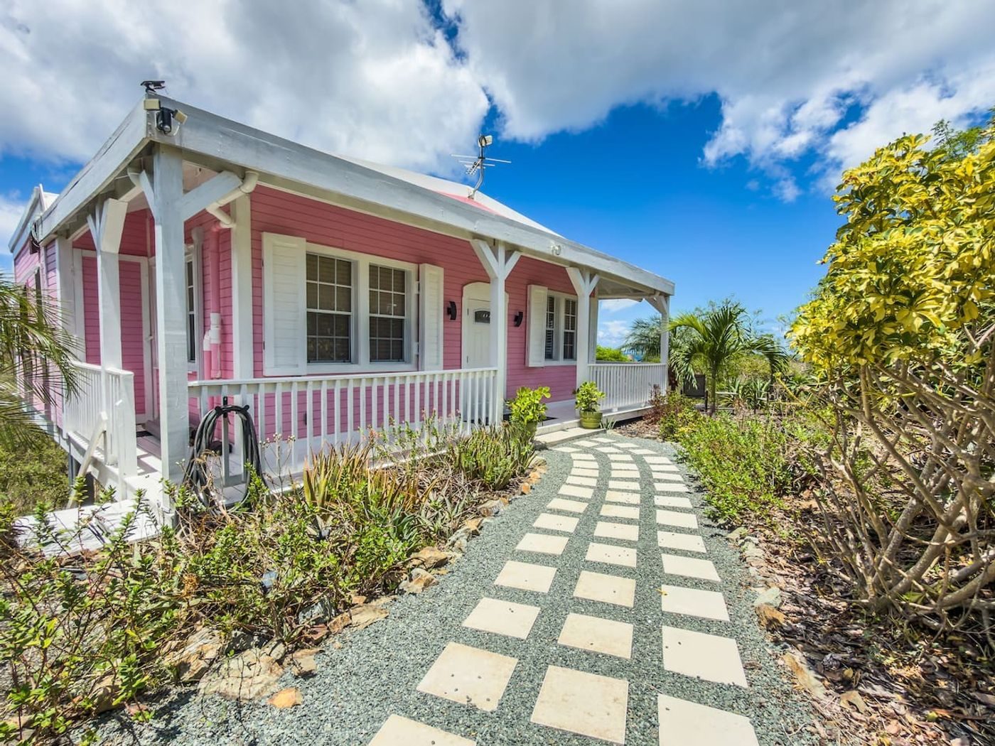 Paved stepping-stone path leading to the pink cottage's porch with white railings