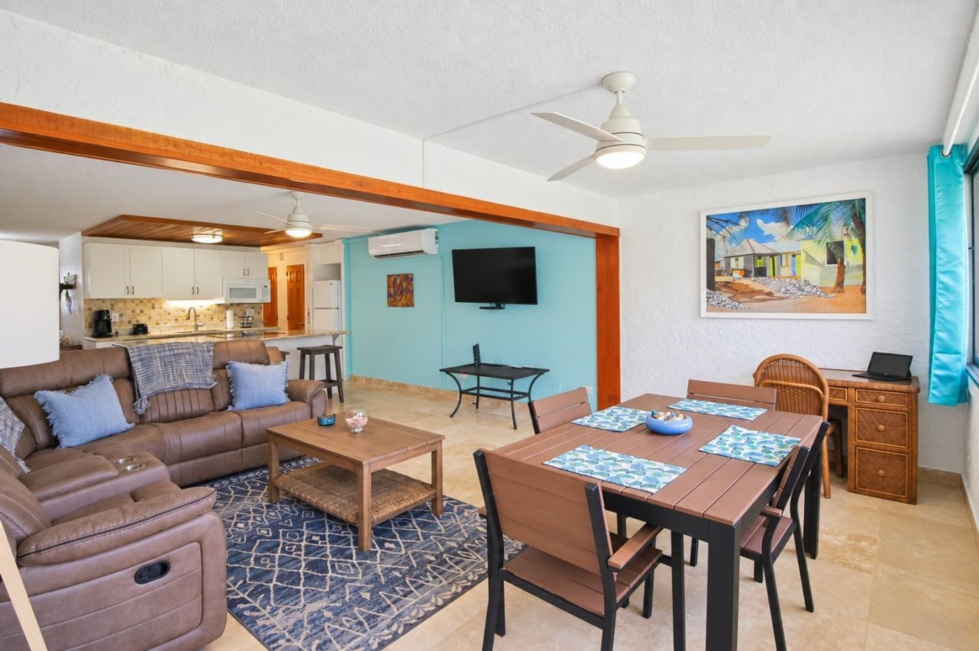 Open living and dining room with a brown sectional sofa, a coffee table and a dining table set for four under a ceiling fan