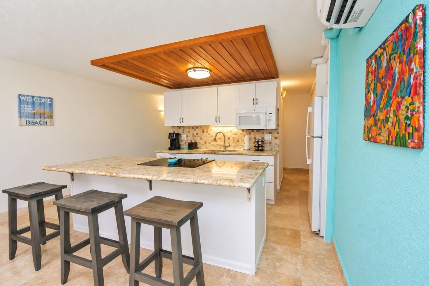 Kitchen with a wood-panelled ceiling, white cabinets, a granite island and three bar stools