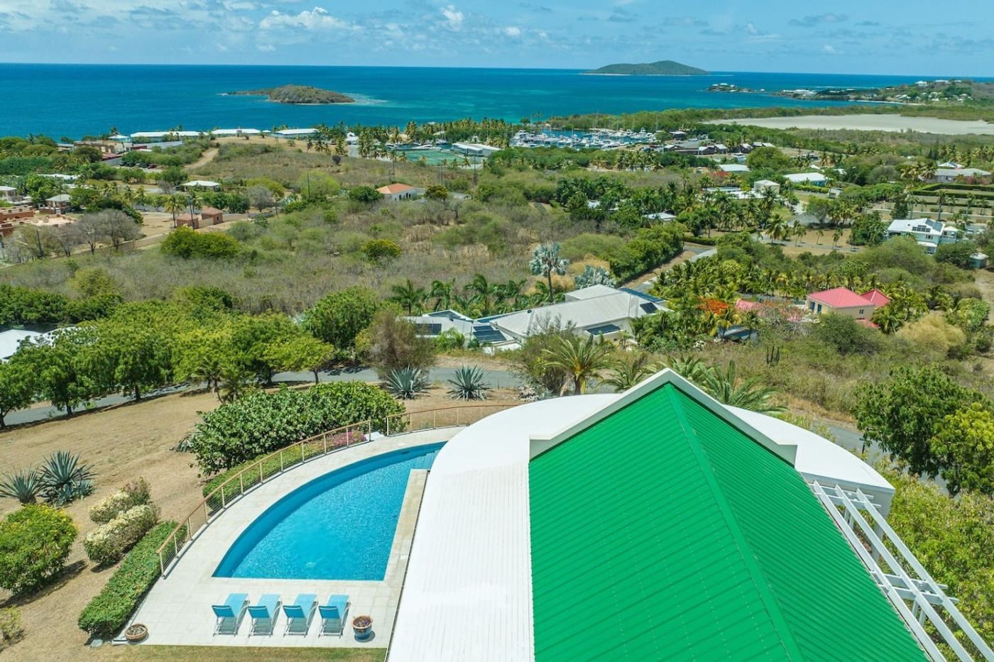 Aerial view of the pool beside the villa's green roof, looking over the hillside to the sea and offshore islands