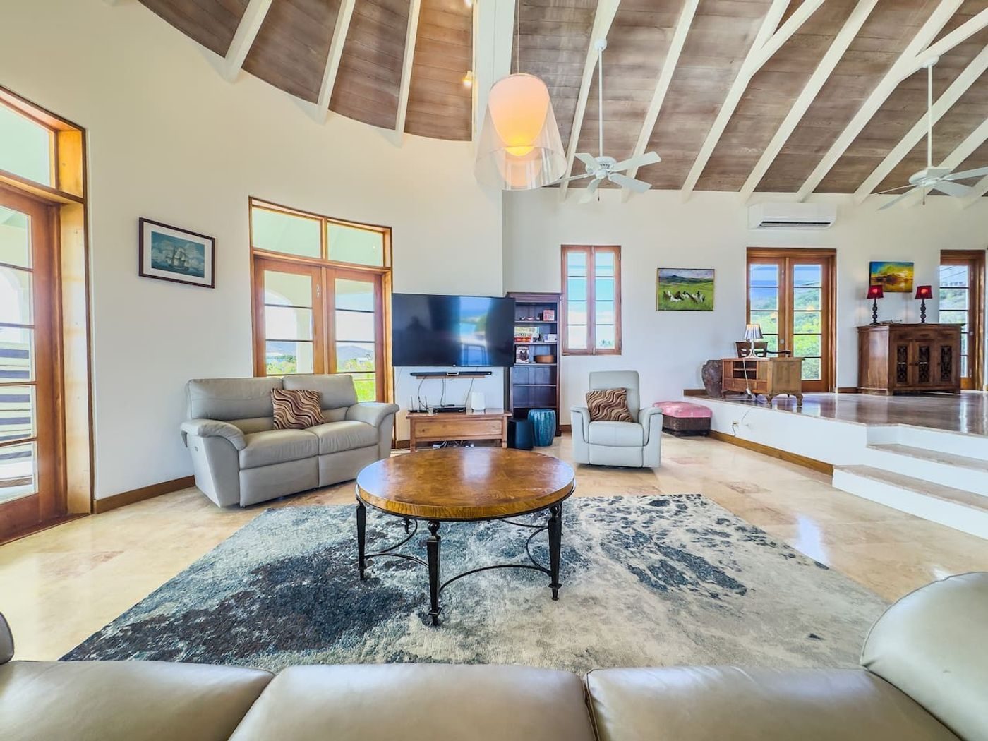 Living room with grey leather sofas, a round coffee table and a vaulted wood ceiling