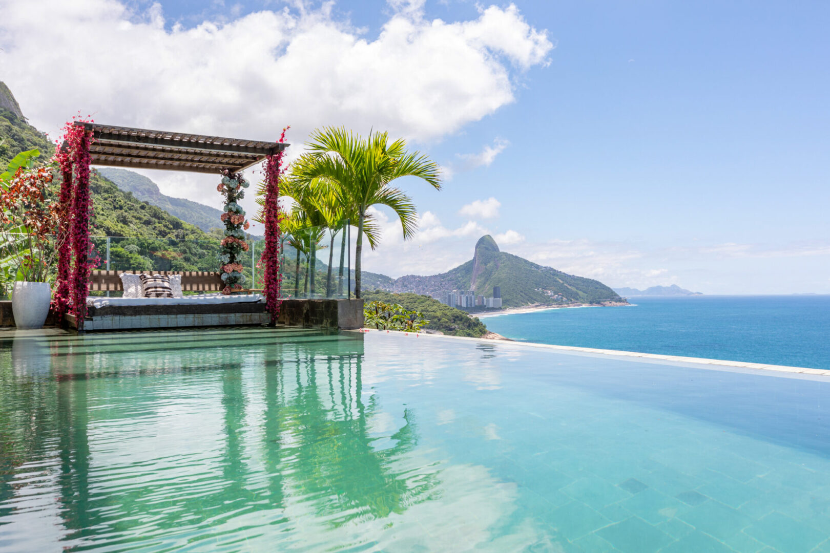 Poolside cabana and daybed on the cliff, with the mountainous Rio coastline in the distance