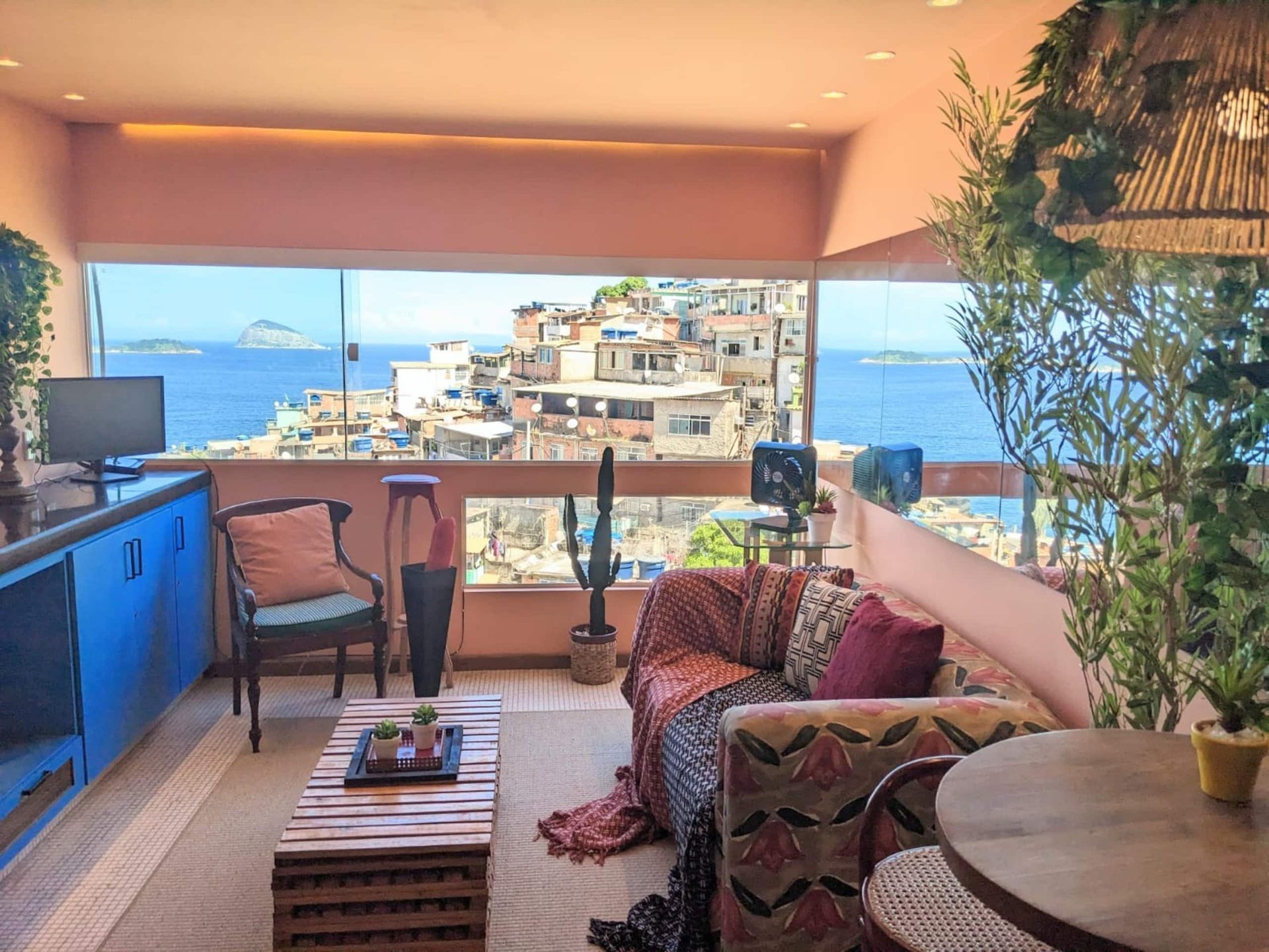 Living room opening onto a private balcony, with the Atlantic, an island and Vidigal's hillside visible through floor-to-ceiling glass