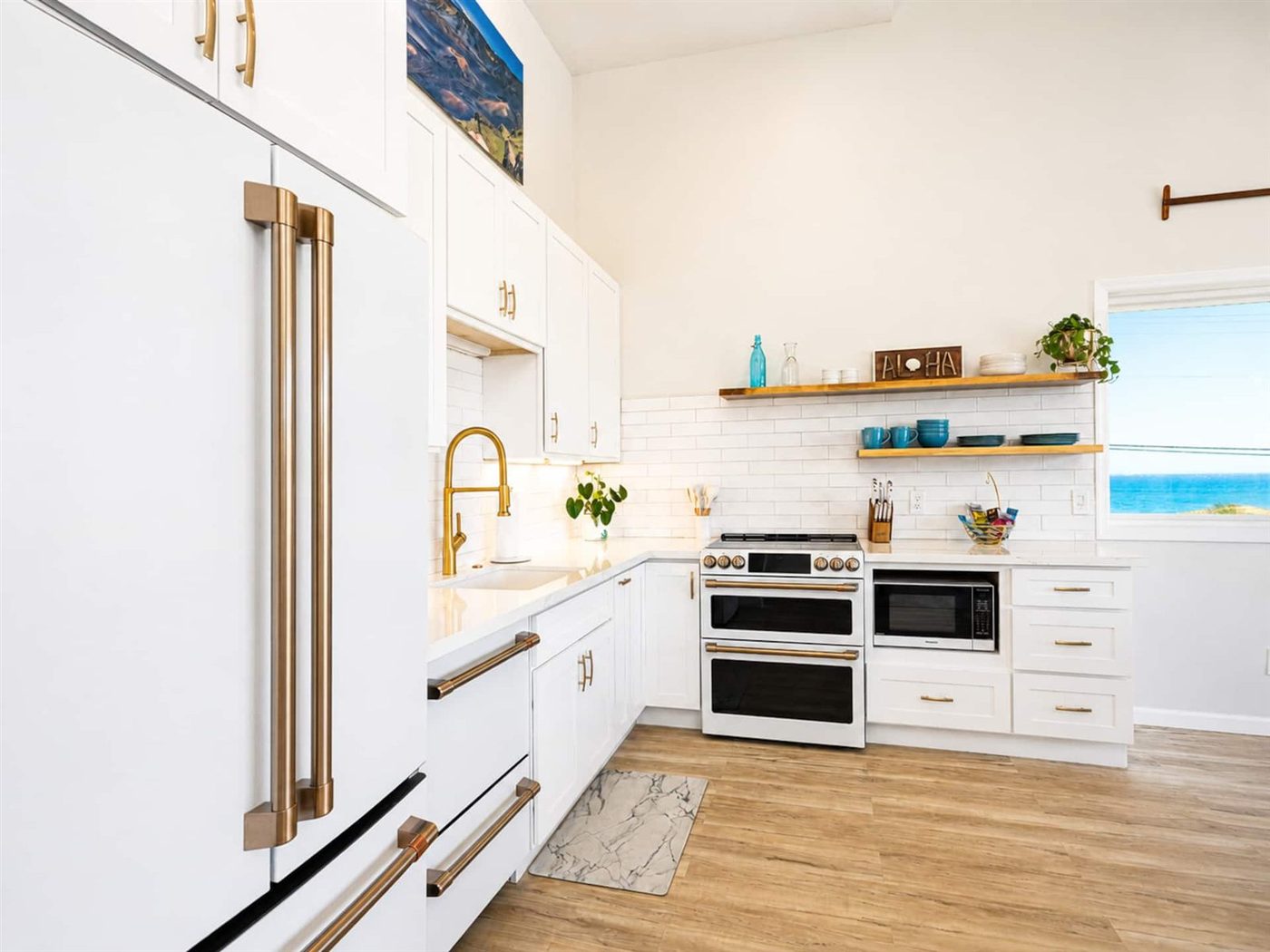 Close-up of the renovated kitchen at Best Ocean Views, with white cabinetry, brass fixtures and the ocean visible through the window