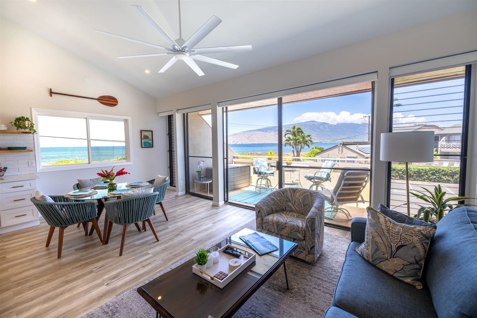 The open living and dining room at Sea Sun Maui, glass doors leading to a lanai with views of the ocean and the West Maui Mountains