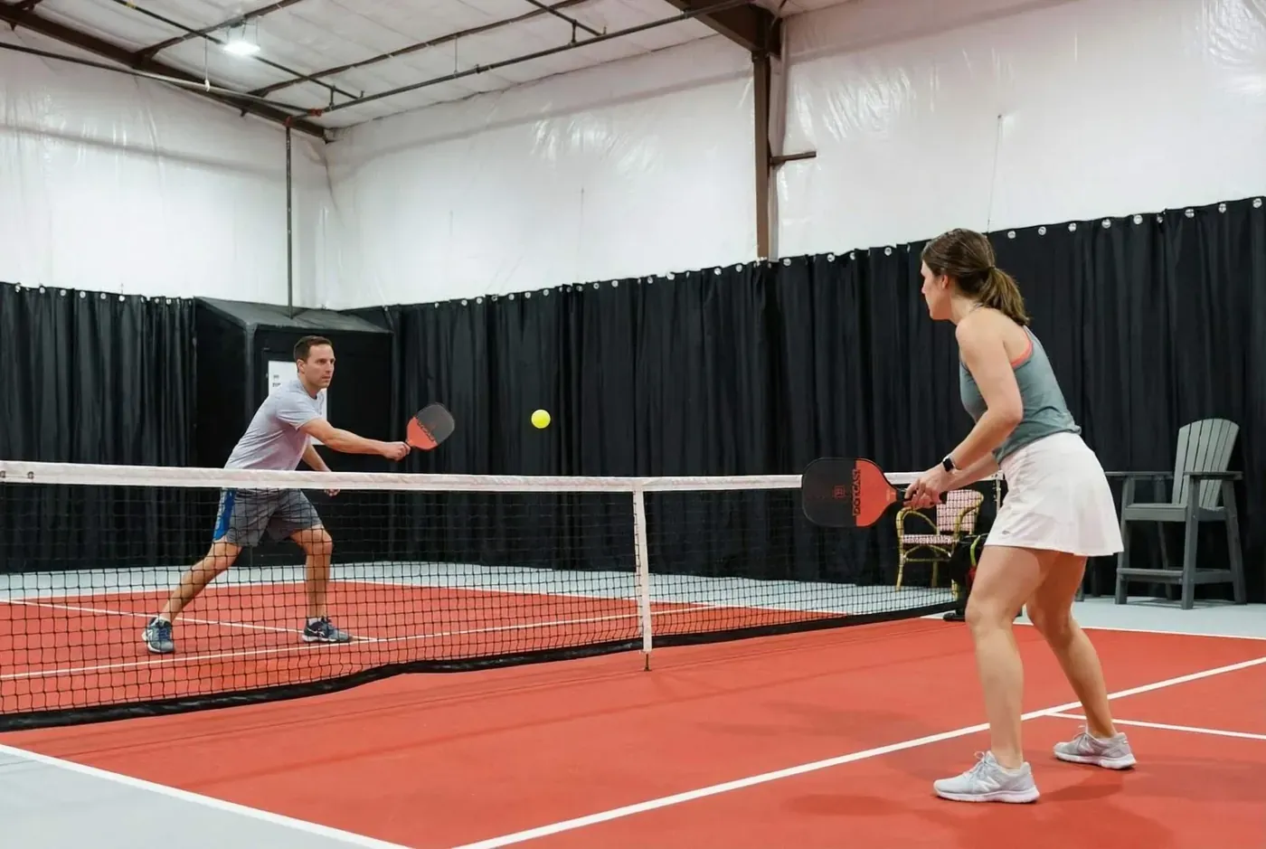 Two guests rally on the private indoor pickleball court, heated and air-conditioned for play in any season