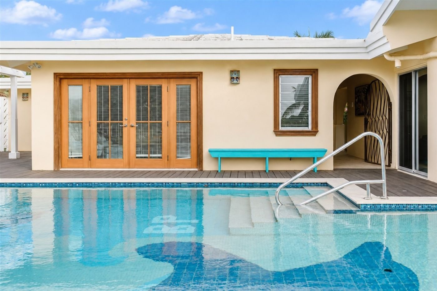 Private pool with broad tiled steps in front of the villa's wooden French doors