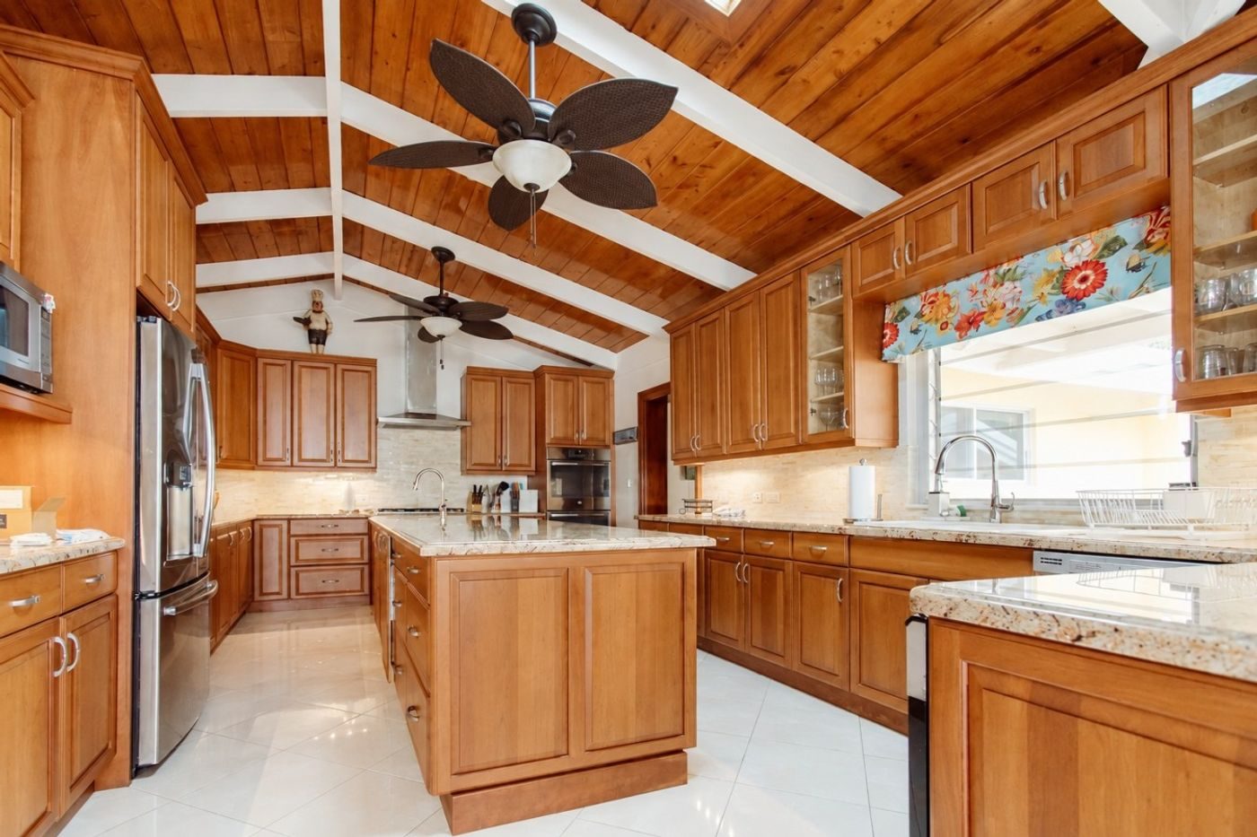 Kitchen with honey-toned wood cabinets, granite counters, an island and a wood-lined pitched ceiling