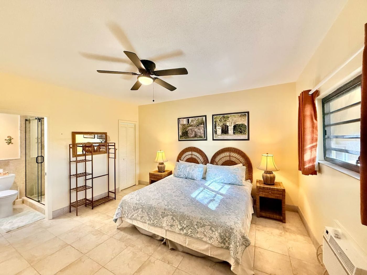 Bedroom with a large bed, a woven headboard, framed prints and a ceiling fan