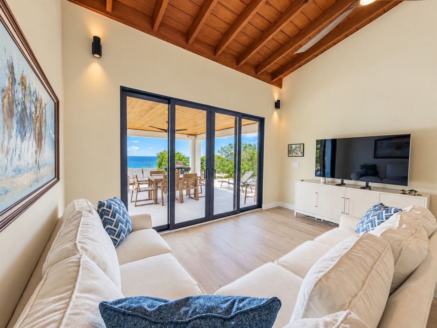 Living room with a white sectional, a large television and black-framed glass doors open to the terrace