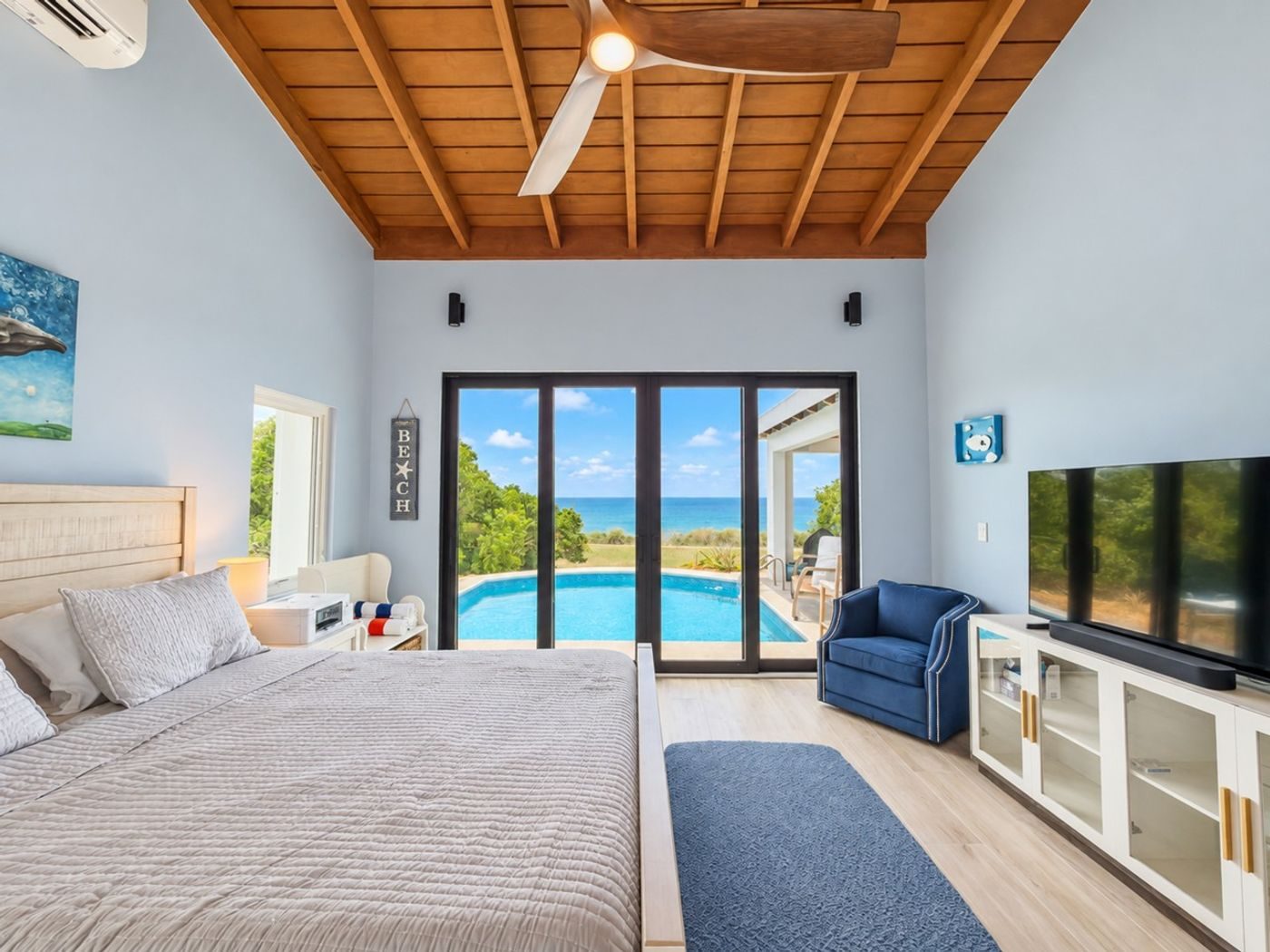 Bedroom with a queen bed and glass doors looking out to the pool and the sea