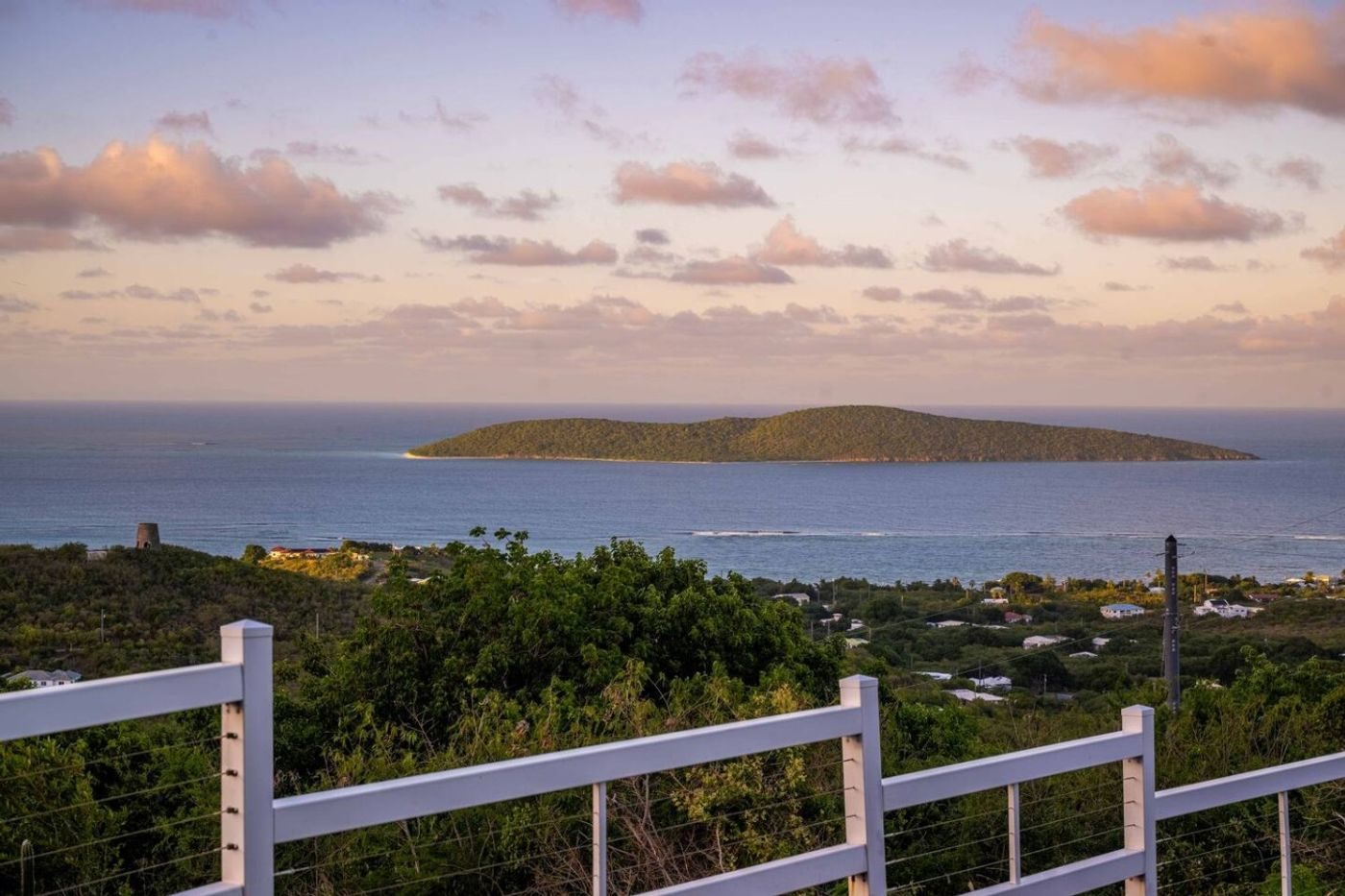 Buck Island seen across the sea from the deck railing, under a pink evening sky