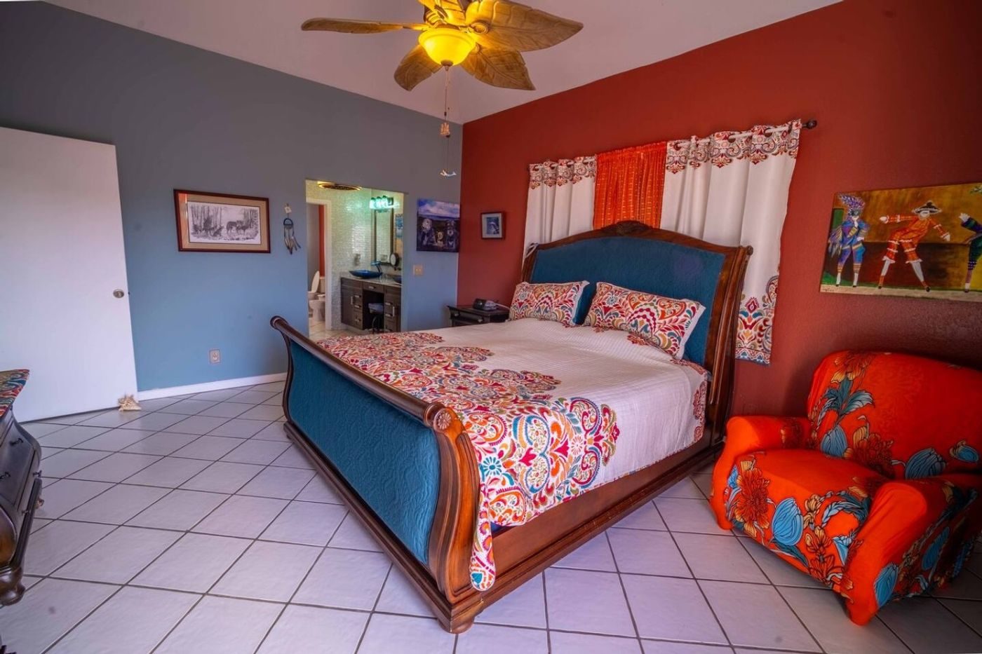 Bedroom with a red accent wall, a teal upholstered bed with a patterned quilt and a red armchair