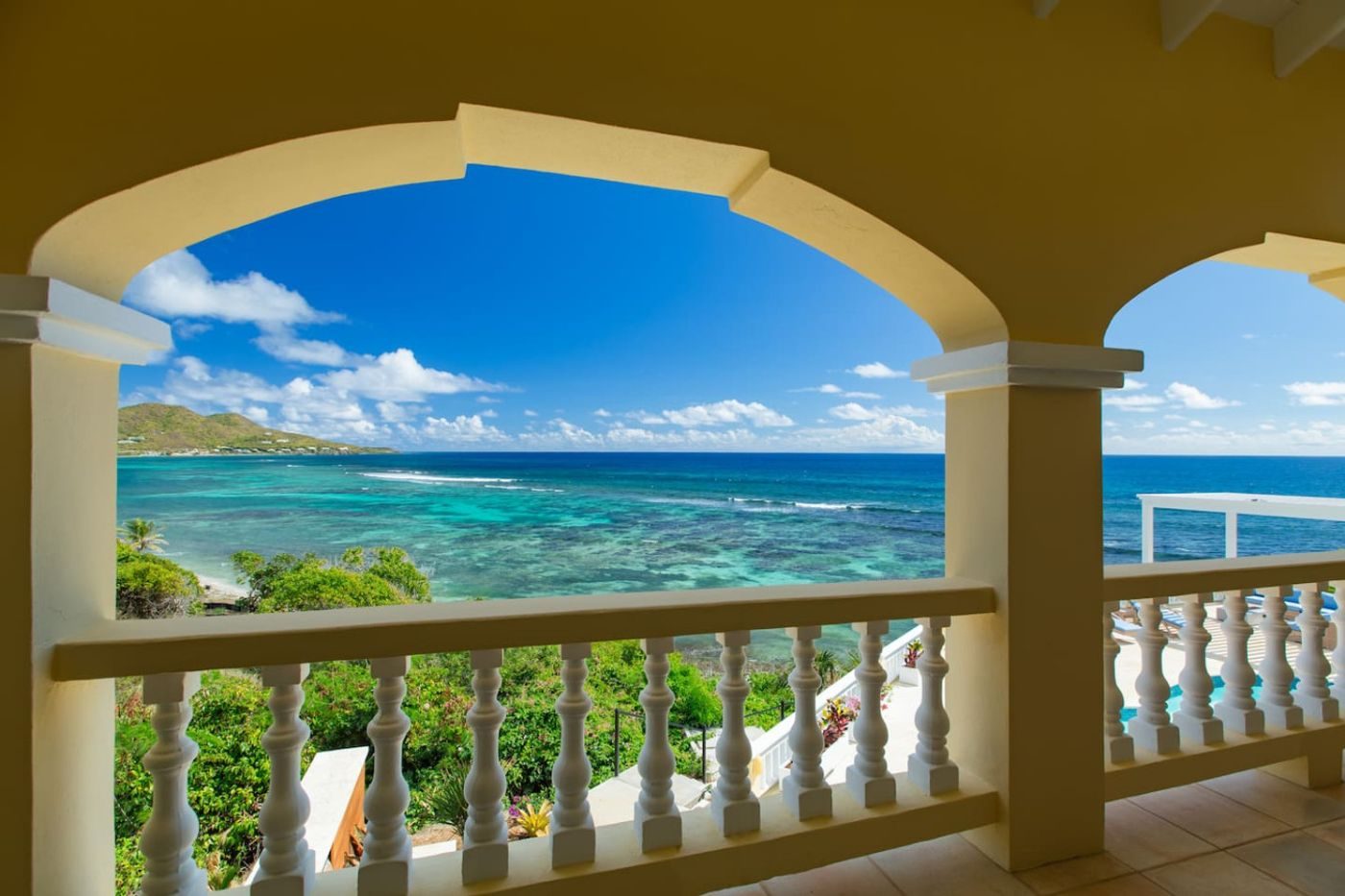 A turquoise bay and a green headland framed by an arch of the villa's veranda
