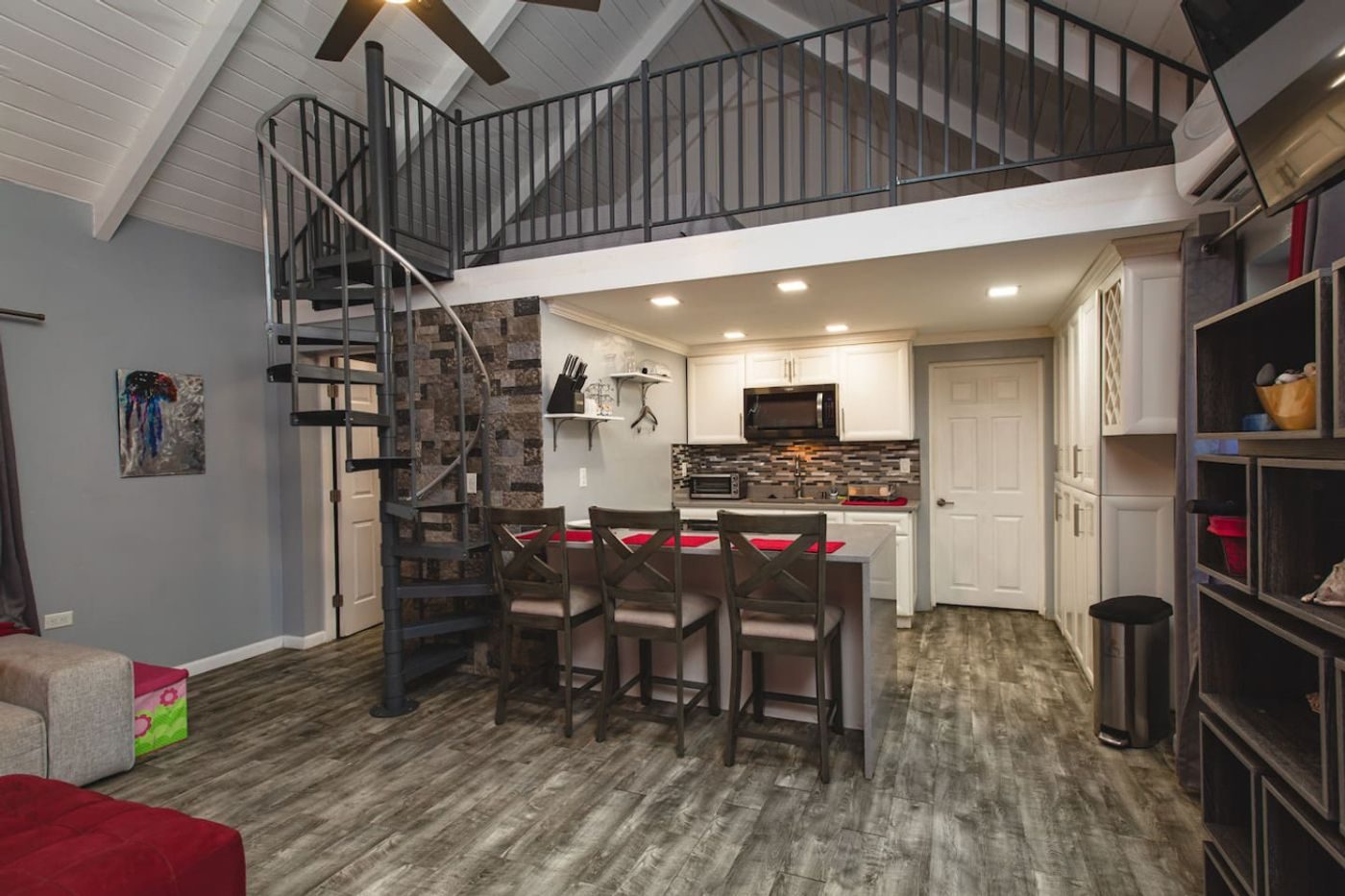 The guest cottage's open kitchen and dining counter beneath a loft reached by a spiral stair