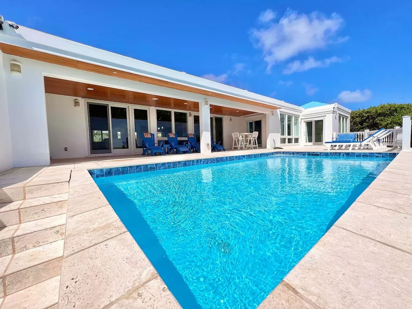 Private pool on a pale stone terrace beside the house's wall of glass doors