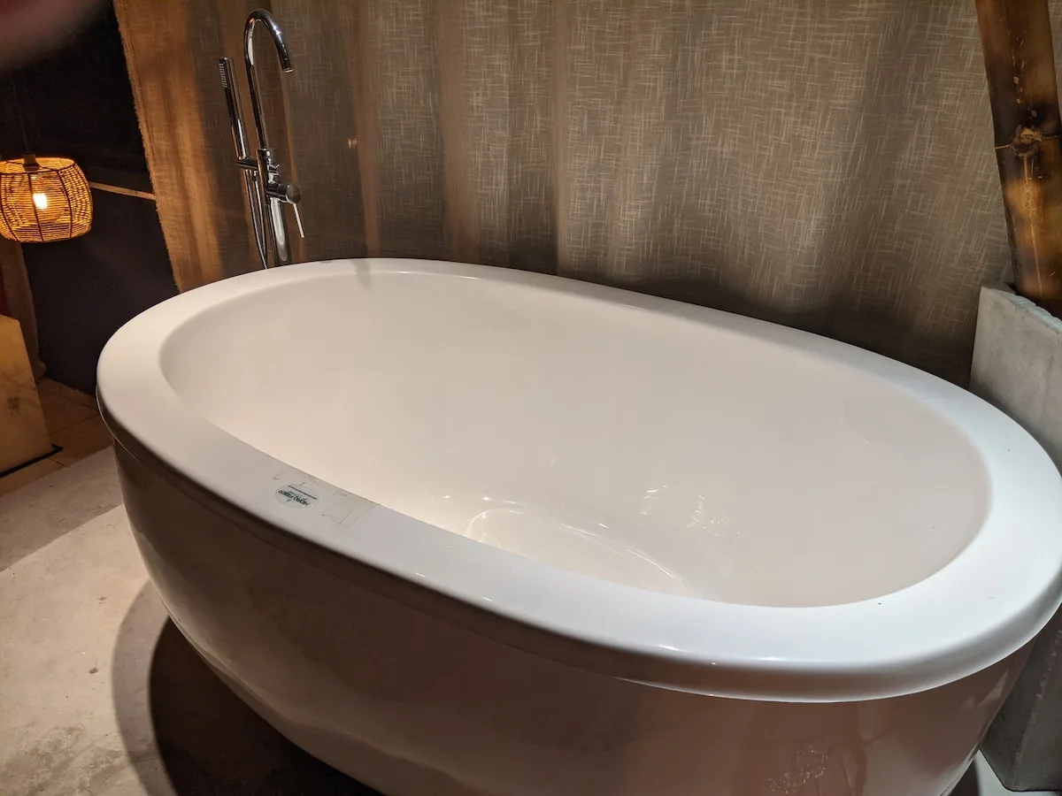 Freestanding soaking tub beside a woven lamp in the suite