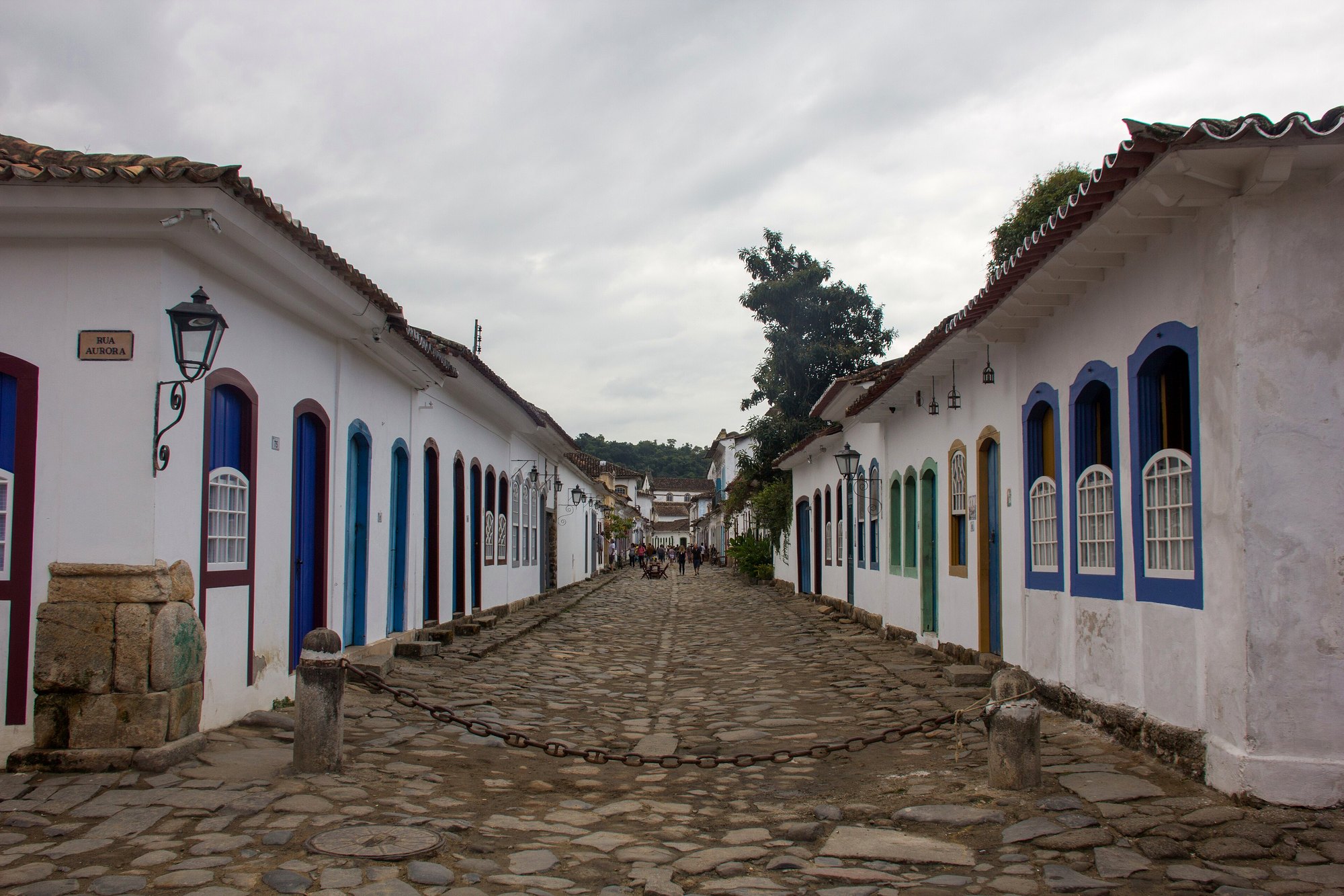 A cobblestone street in Paraty's historic center lined with whitewashed colonial shopfronts and colorful doors