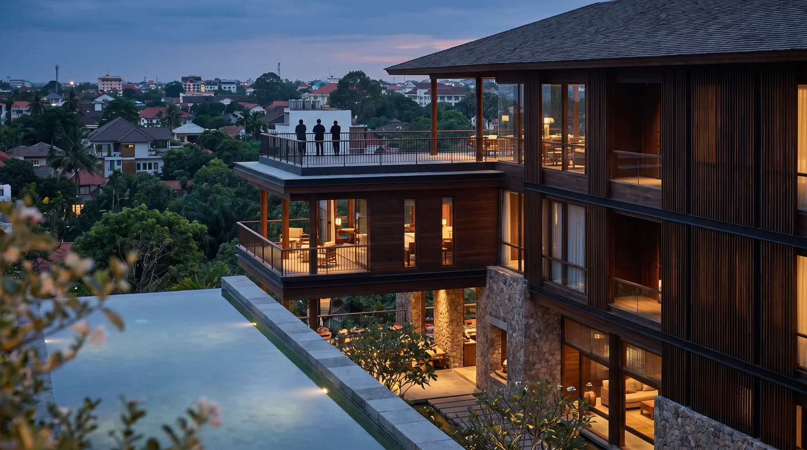 Modern luxury hotel exterior at dusk in a Southeast Asian city.